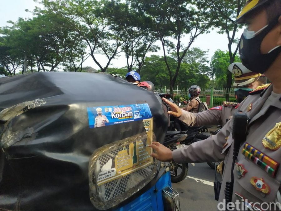 Sejumlah petugas memasang stiker agar mematuhi praturan lalulintas dan juga prokes covid-19 dalam Operasi Zebra 2020. (foto: detik.com)