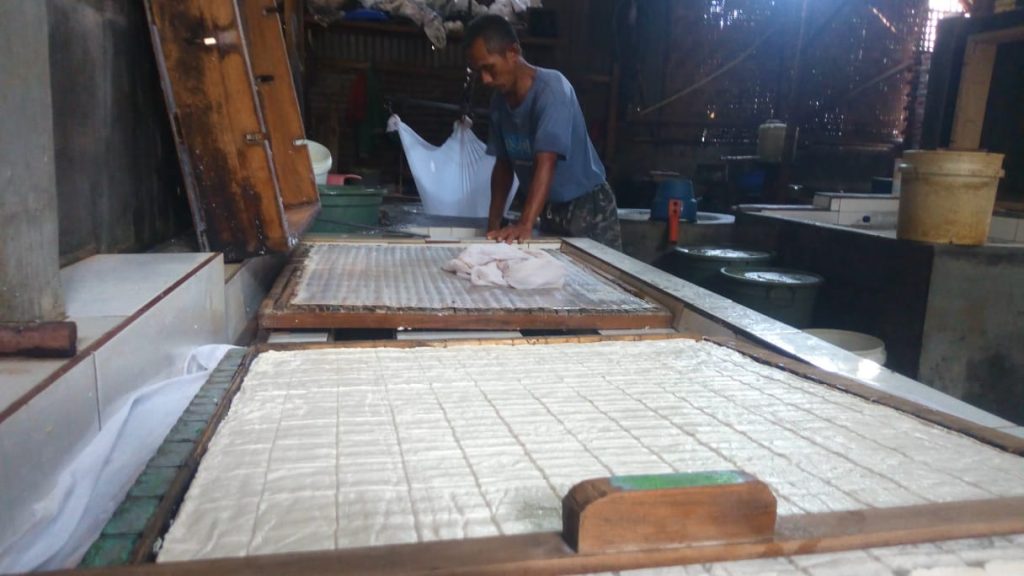 Seorang pengusaha tahu tengah melakukan proses pemotongan. (Foto: Radar Jember)