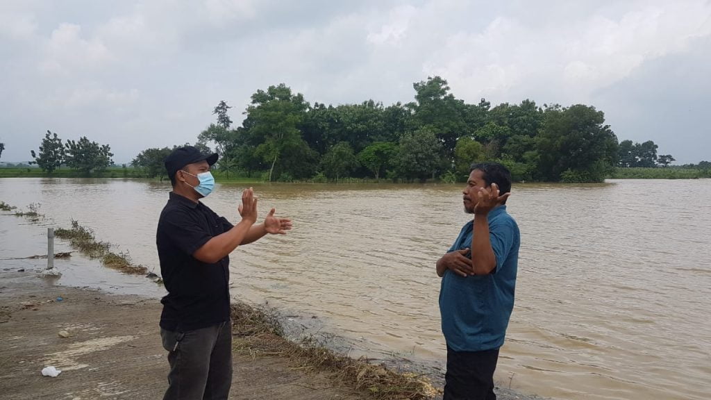 Anggota DPRD Kabupaten Sumedang, Deni Agus Setiawan bersama Kades Sukamulya meninjau banjir yang merendam sawah akibat luapan Sungai Cihaur, Senin (18/1/2021). (Foto: IST)