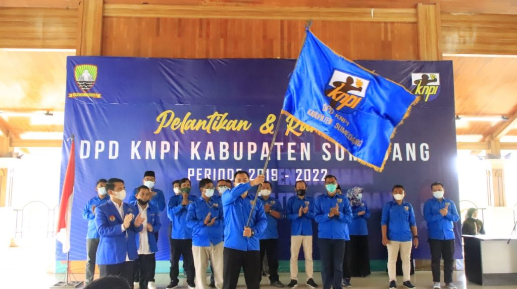 Ketua DPD KNPI Sumedang, Ekky Ahmad Muzaki Ramdhani, mengibarkan bendera KNPI di acara pelantikan pengurus KNPI Sumedang periode 2019-2022