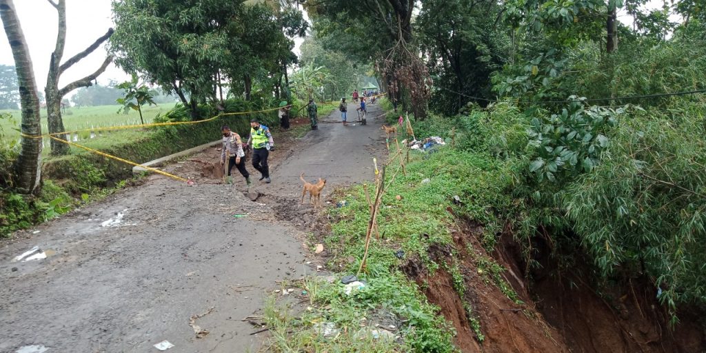 Sejumlah petugas memantau kondisi Jalan Raya Conggeang-Ujungjaya Blok Enjang Desa Cacaban Kecamatan Conggeang Kabupaten Sumedang yang ambles hingga tak bisa dilalui kendaraan, Senin (8/2/2021). (Foto: Fajarnusantara.com)