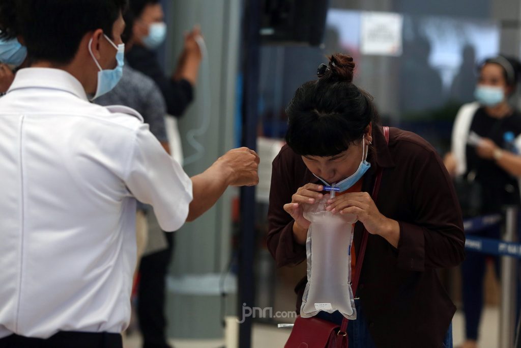Petugas kesehatan di Stasiun Pasar Senen, Jakarta Pusat memberikan petunjuk kepada calon penumpang kereta api tentang cara menggunakan GeNose C19. (Foto: Ricardo/jpnn.com)