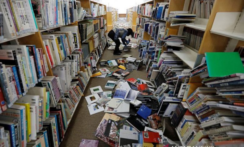 Seorang staf perpustakaan mencoba merapikan buku - buku yang berjatuhan dari rak akibat gempa bumi kuat di Kota Iwaki di Iwaki, Prefektur Fukushima, Jepang 14 Februari 2021. (Foto: Dok/ANTARA/REUTERS/Issei Kato/pri).