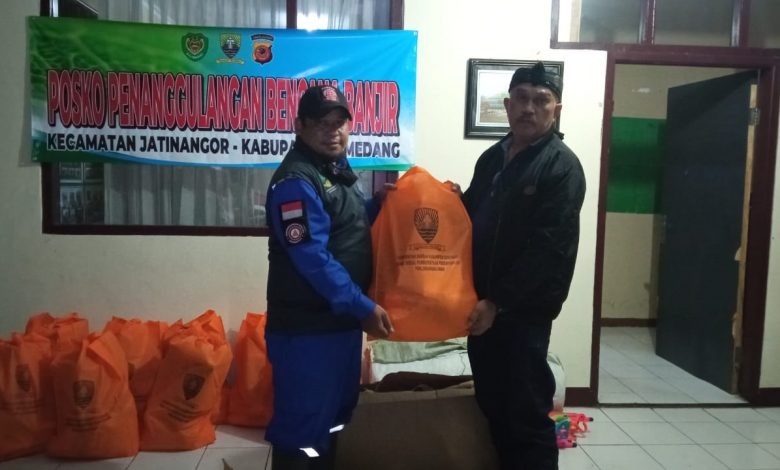 Photo : Anggota Tagana Kab Sumedang menyerahkan bantuan Logistik dan alat kebersihan