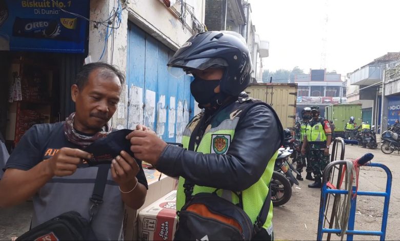 Babinsa Koramil 1004/Tanjungsari saat membagikan masker kepada warga yang kedapatan tidak memakai masker disaat PPKM Level 3